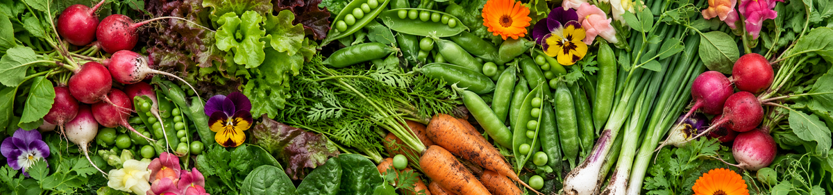 A dense overhead assortment of fresh spring vegetables and flowers.